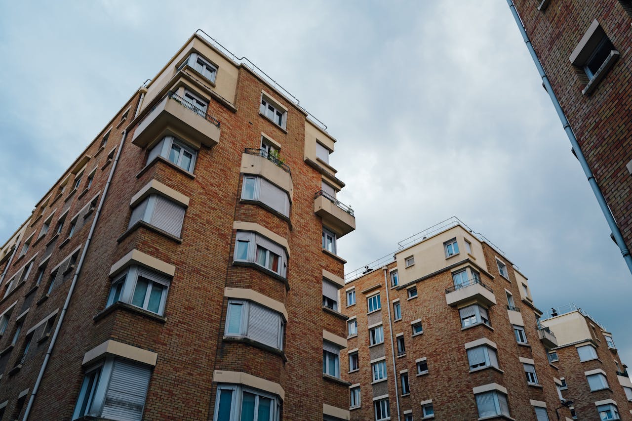 Urban brick apartment buildings under a cloudy sky, showcasing city living architecture.