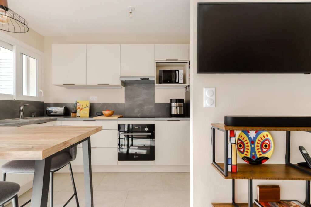 Bright modern kitchen featuring sleek cabinetry, appliances and a unique decorative plate.